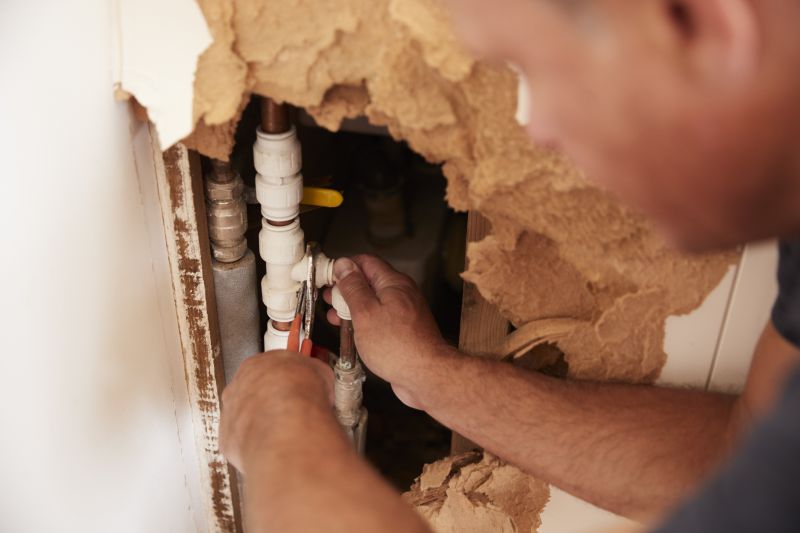 Plumber repairing a pipe in a wall